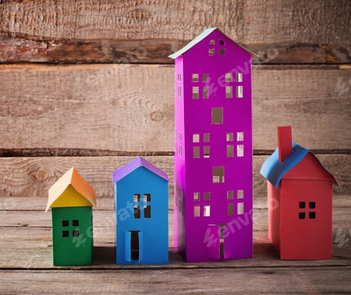 Preview: A Paper Houses Stands Over A Wooden Background.