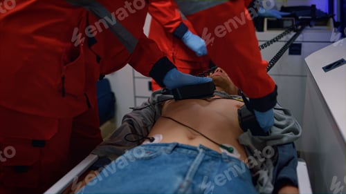 Preview: Emergency Medical Doctors Hands Using Heart Defibrillator On Patient Chest In Ambulance Car. Ems