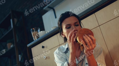 Preview: Portrait Of Joyful Woman Enjoying Burger And Glass Of Wine In Night Kitchen. Smiling Female