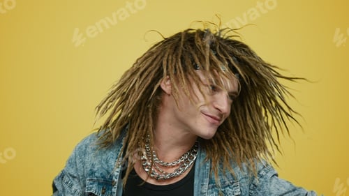 Preview: Portrait Of Joyful Rocker Dancing On Yellow Background. Smiling Man Waving Head With Dreadlocks