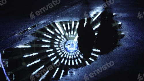 Preview: Mirroring Of Ferris Wheel In Water Surface On Urban Street. Reflection Of Unknown Couple Running On