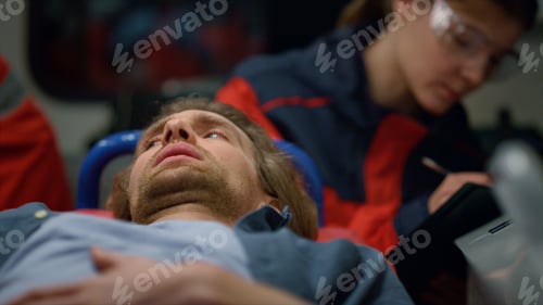 Preview: Male Patient Lying On Stretchers In Emergency Vehicle. Exhausted Man Feeling Pain In Stomach