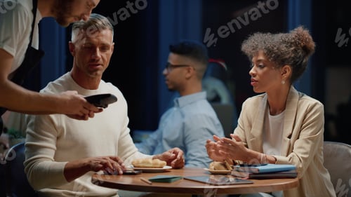 Preview: Mixed Race Business Woman And Businessman Meeting In Cafe At Evening. Multi Ethnic Team Talking