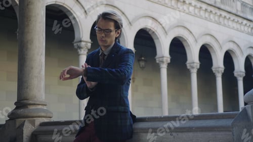 Preview: Serious Student Standing In University Hallway. Young Man Checking Time On Wristwatch Outdoors