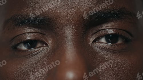 Vista previa: Extreme Closeup Surprised Brown African Male Eyes Looking At Camera. Portrait Of Young African Guy