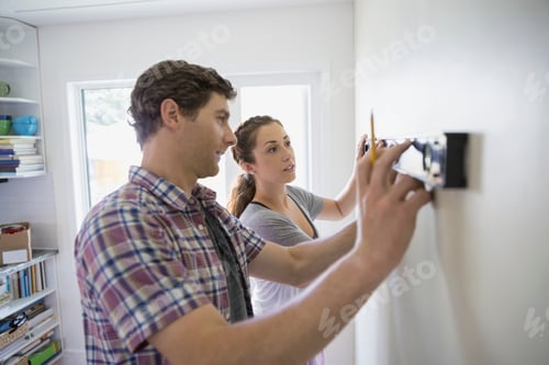 Preview: Couple Using Level Tool On Living Room Wall