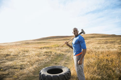 Preview: Man Hammering Tire In Sunny Rural Field