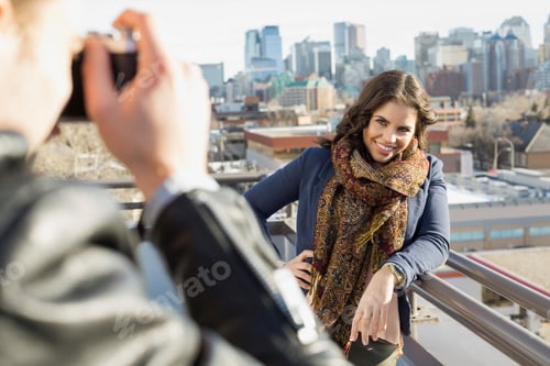 Preview: Man Photographing Woman On Patio Against Cityscape