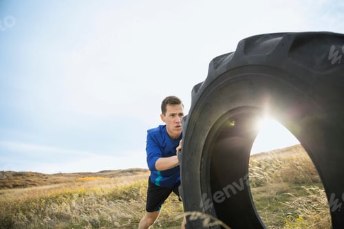 Preview: Man Pushing Tire In Sunny Rural Field