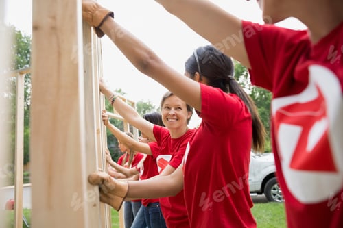 Preview: Smiling Volunteers Lifting Construction Frame