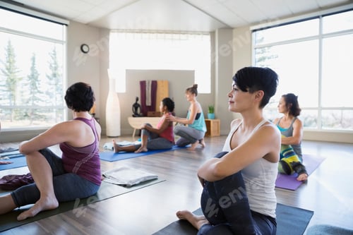 Preview: Women Practicing Seated Twist Pose In Yoga Class