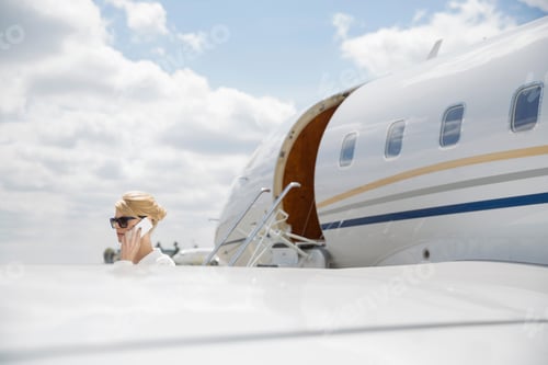 Preview: Businesswoman Talking On Cell Phone Near Corporate Jet
