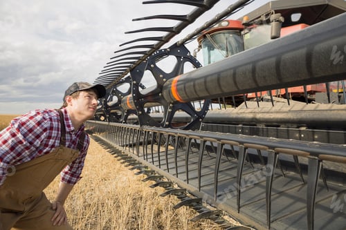 Preview: Farmer Examining Equipment On Combine Harvester