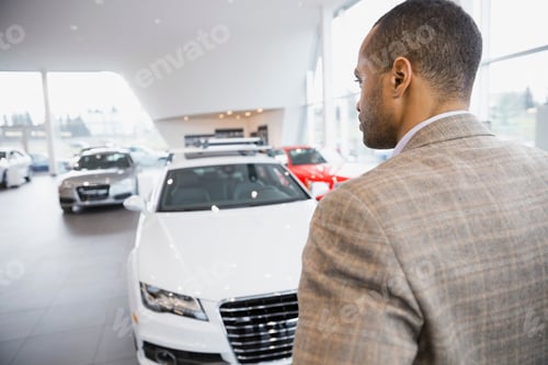 Preview: Man Looking At Cars In Car Dealership Showroom