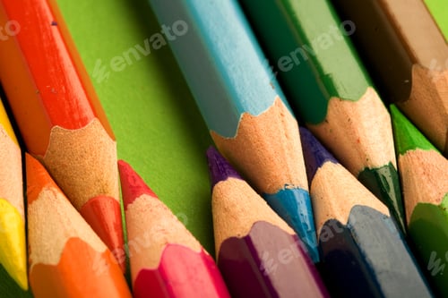 Preview: Close Shot Of A Row Of Colored Pencils Against A Green Background.