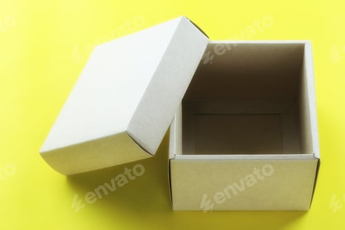 Preview: Empty Brown Paper Box Rests On A Yellow Paper Floor And Have Copy Space For Design In Your