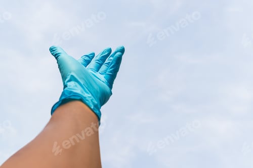 Preview: Gloved Hand Reaching Up Toward Pale Blue Sky
