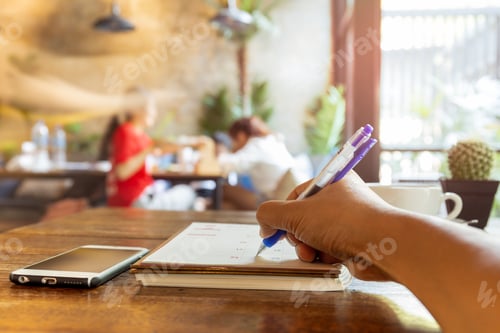 Preview: Businessperson Hand Writing Schedule In Calendar Diary With Pen On Table.