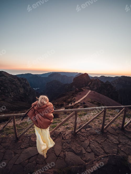 Preview: A Back View Of A Woman Admiring Nature While Standing By The Fence At The Top Of A Mountain At