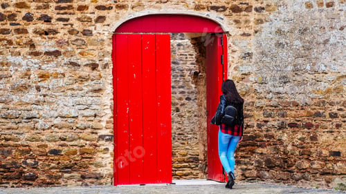 Preview: A Closeup Shot Of A Young Female Entering Through A Red Wooden Gate In A Brick Wall