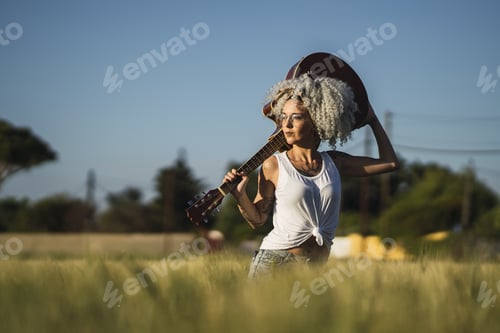 Preview: A Curly-Haired Spanish Cute Woman Posing In A Wheat Field With An Acoustic Guitar