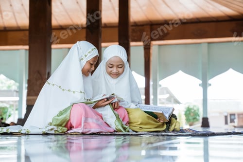 Preview: Two Asian Muslim Girls Reading And Studying The Holy Book Of The Al-Quran Together Sitting On The