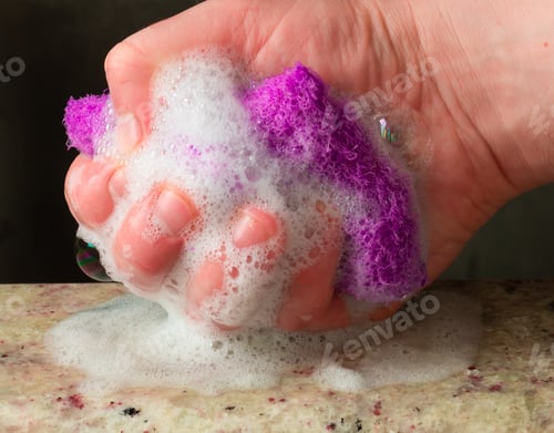 Preview: Close-Up Photo Of A Hand Squeezing A Purple Sponge With Soap Dripping On The Countertop