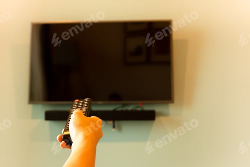 Preview: Hand Holding Tv Remote Control In Front Of Widescreen Tv Set With Blank Screen.