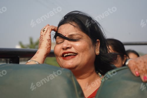Preview: An Indian Woman In An Open Bus Smiling And Touching Her Hair With Closed Eyes During A Windy Weather