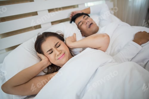 Preview: Portrait Of Woman Blocking Ears With Man Sleeping Snoring On Bed