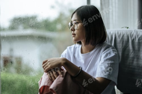 Preview: A Woman In A White Shirt Sitting On The Bed And Looking Out.