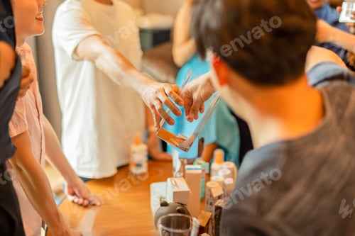 Preview: Man Taking Paper Piece From Plastic Box With Friends In Background.
