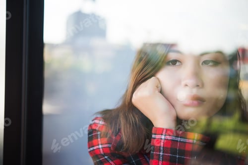 Preview: Portrait Of Young Woman Gloomy Sitting Near A Window At Home.