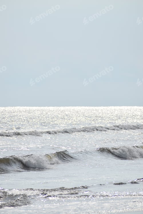 Preview: A Vertical Shot Of Sea Waves Under The Sunlight And A Blue Sky