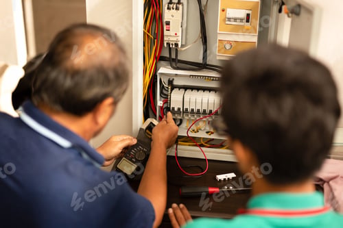 Preview: Senior Electrician Teaching Trainee Measuring Voltage In Fuse Board.