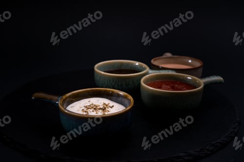Preview: The Bowls Of Different Flavored Sauces On A Black Surface