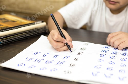 Preview: School Boy Doing Home Work Hand Writing Answers An Excercise Book Indoors