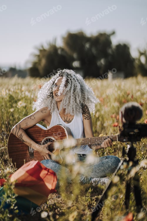 Preview: A Curly-Haired Spanish Cute Woman Playing Guitar In A Field Of Daisies While Recording A Vlog