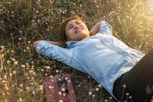 Preview: Young Hipster Woman Lying In Flower Field After She Tired For Reading Soft And Blurred Background