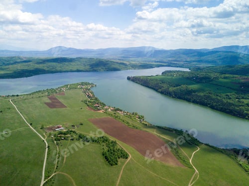 Preview: An Aerial Shot Of The Green Landscapes, Fields And A River Under The Cloudy Sky On A Sunny Day