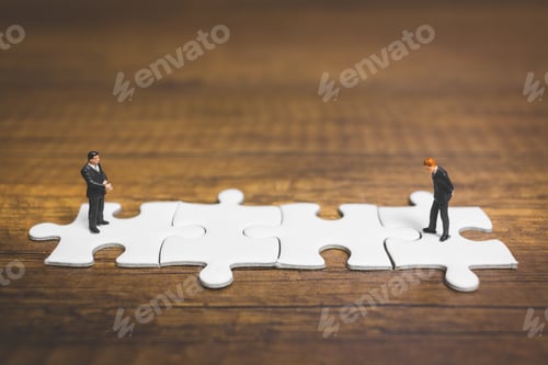 Preview: Miniature People: Businessman Standing On Jigsaw With Wooden Background : Business Concept.