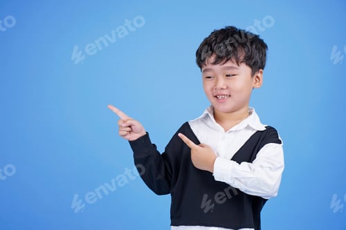 Preview: Close Up Portrait Of Cute Boy Pointing With Finger Gesture, Isolated On Blue Background