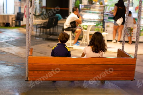 Preview: Children Sitting On A Swing In Shopping Mall At Night.