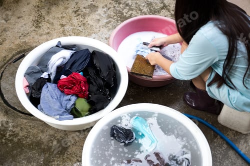 Preview: Woman Hands Washing Dirty Clothes On Wooden Board With Clothes Brush In A Big Bowl On Concrete Floor