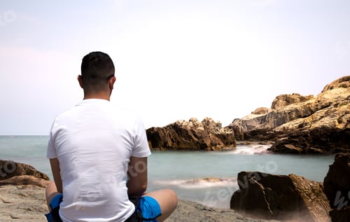 Preview: Man Sitting On The Rock Doing Meditation By The Sea In Day Time