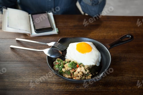 Preview: Woman With Cell Phone Having Stir Fried Chicken Chili And Thai Basil With Fried Egg On Top In