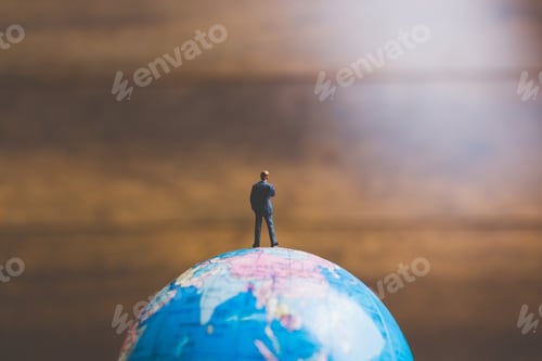 Preview: Miniature People , Businessman Standing On The Globe World Map With Brown Background And Copy Space