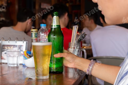 Preview: Female Hand Holding Bottle Of Beer On Table In Reataurant.