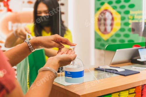 Preview: Women Washing Hands With Alcohol Gel At Clothes Store Counter
