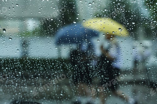 Preview: Blurred People Crossing Street Holding An Umbrella On A Rainy Day